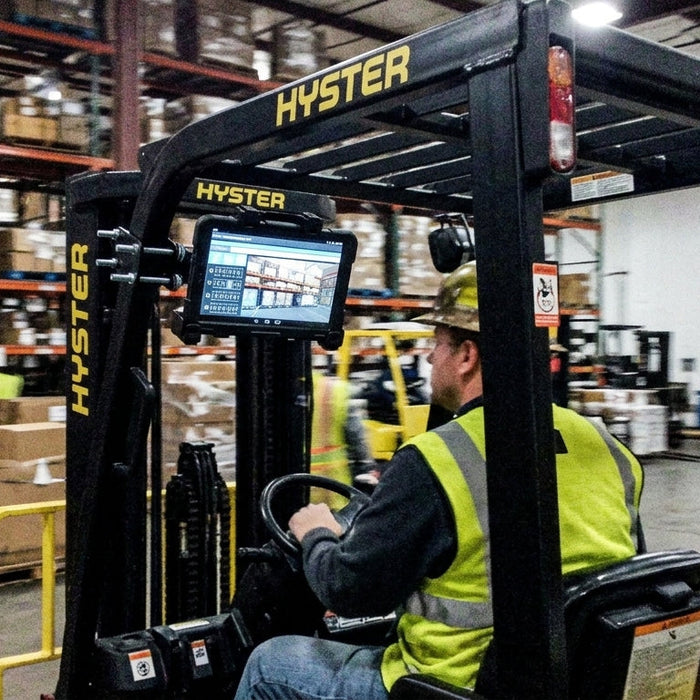 Image of a forklift driver in a warehouse look at a tablet screen