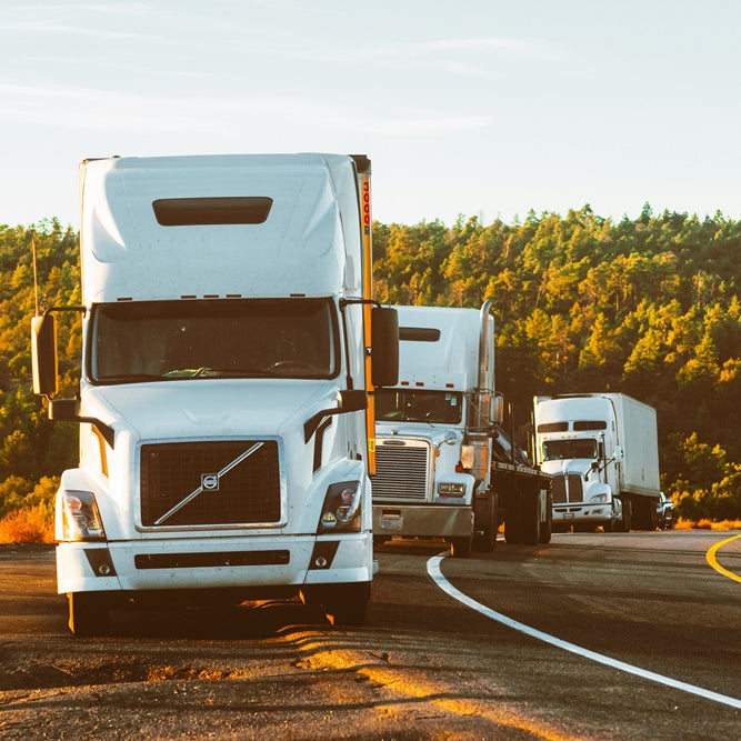 Three white trucks parked up on a US road during sunrise