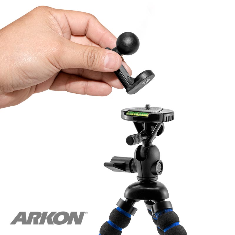 A hand holds the 1/4-20 Camera Tripod Bolt to 22mm Ball Adapter above a small black tripod adapter with flexible legs and bubble level, with the ARKON logo in the bottom left corner.