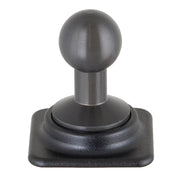 A close-up of a black coffee tamper with a textured handle and flat base, upright on a square black platform next to an Arkon HD Series 20mm Aluminum Ball to Dual T-Tab Adapter.