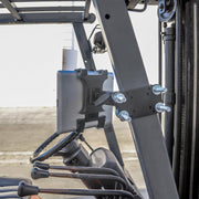 A 7 inch Robust Forklift Front Guard Slim-Grip® Tablet Mount is installed inside a forklift near the steering wheel and controls, with part of the forklift frame and outdoor pavement visible in the background.