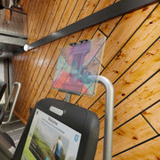 Close-up of a treadmill display showing a welcome screen and the Slim-Grip® Ultra Pro Universal Tablet Holder with Clamp Mount in a gym with wooden paneled walls. Other equipment and a balcony are visible in the background.