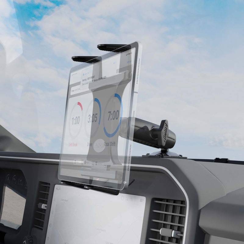 A Slim-Grip® Tablet Holder with Drill Base Mount secures a tablet on the vehicle dashboard, displaying time tracking data, while clouds are visible through the windshield in the background.