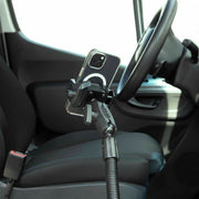 A smartphone is secured in the RoadVise® Ultra Holder with Shaft Arm and 18 Seat Rail Mount, attached near the driver’s seat beside the steering wheel and above the seatbelt buckle.