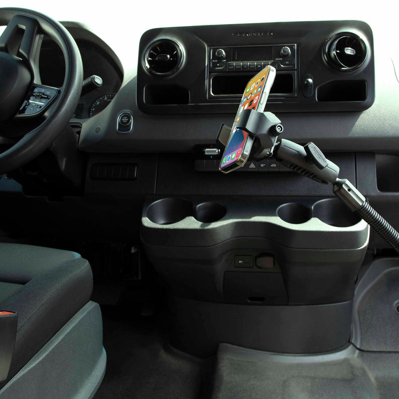 A RoadVise® Ultra Holder with Shaft Arm and 18 Seat Rail Mount secures a smartphone above the cup holders in the center console, with the steering wheel and dashboard controls visible.