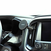 A Magnetic Phone Holder with Vent Mount - MagSafe Compatible is secured to a car’s air vent near the dashboard, with part of the steering wheel and infotainment screen visible.