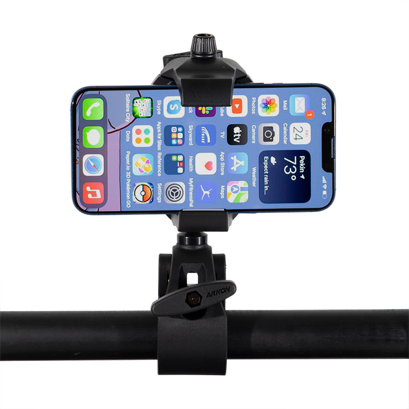 A smartphone is mounted horizontally in a RoadVise® Ultra Holder with Multi-Angle Arm and Clamp Mount, attached to a bar, showing various app icons and weather information on its screen.