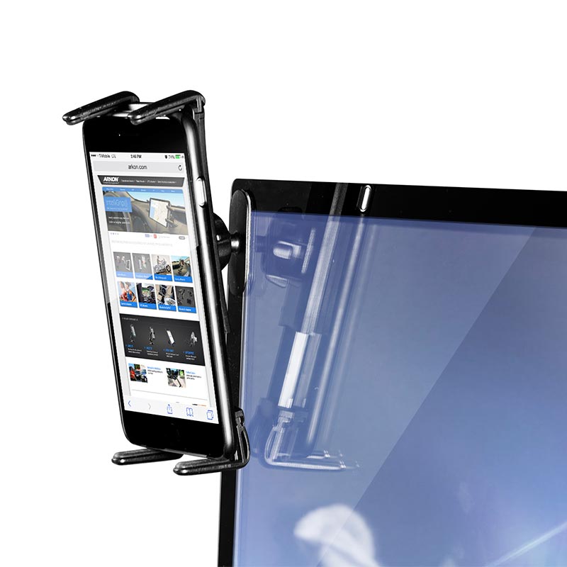A smartphone is secured in the Adhesive Car Mounting Pedestal - Dual-T Compatible, which is attached to the top edge of a computer monitor and displays a website on the phone’s screen.