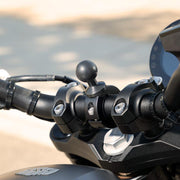 Close-up of the Aluminum Motorcycle Handlebar Mount - 25mm (1 inch) Compatible, securely attached to a motorcycle handlebar. The mount features a ball head for phone or GPS and visible screws, with the background softly blurred.