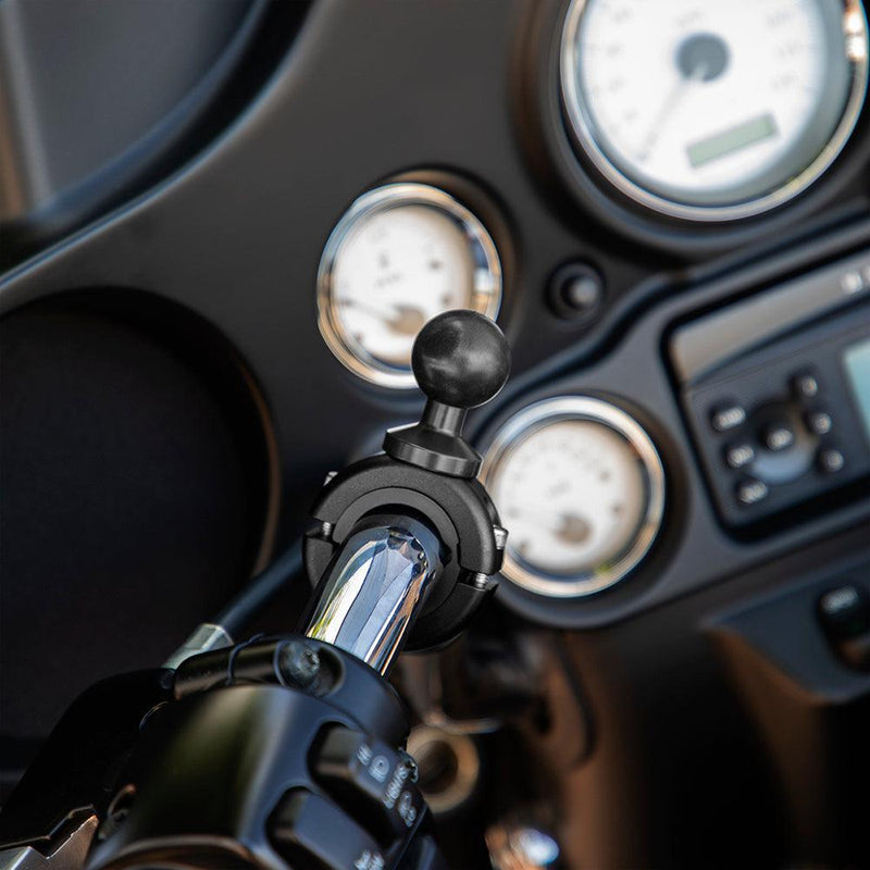 A close-up of a motorcycle handlebar shows the Aluminum Motorcycle Handlebar Mount - 25mm (1 inch) Compatible securely holding a phone or GPS, with an instrument panel and gauges visible in the background.