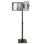 The TW Broadcaster Combo Slim-Grip® Ultra 29-inch Stand Holder securely mounts both a tablet and smartphone side by side, showing a woman in a hat live streaming with visible comments and reactions on both screens.