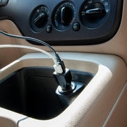 A close-up shows two charging cables plugged into the Car Charger with Quick Charge 3.0 and USB A Ports, connected to a car’s cigarette lighter socket, with the dashboard and air conditioning controls in view.
