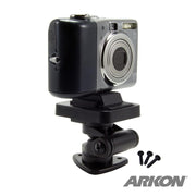 A digital camera is mounted on the Multi-Angle Adhesive or Drill Base Mount with a 1/4-20 camera mounting pattern in black, accompanied by three screws. The ARKON logo is visible in the bottom right corner.