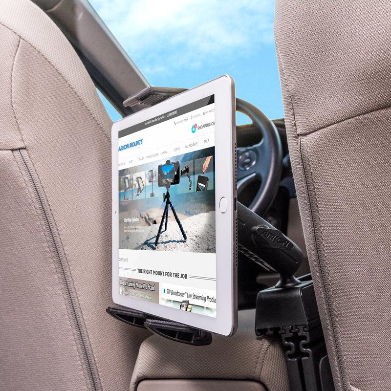 The Car Seat Console Wedge Tablet Mount secures your tablet on the back of a car seat with a black adjustable holder, perfectly positioning it for rear passenger viewing with the steering wheel and dashboard visible in the background.