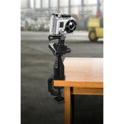 The Clamp Mount for GoPro HERO Action Cameras is attached to a wooden table edge in an industrial setting with a blurred background—ideal as a live streaming accessory.