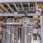 Close-up of a forklifts lifting mechanism with metal parts, chains, and a MAX CAP 5000 LB label. Warning stickers and a LockVise™ Metal Locking Overhead Guard Tablet Mount with Multi-Pivoting Arm are also visible on the machinery.