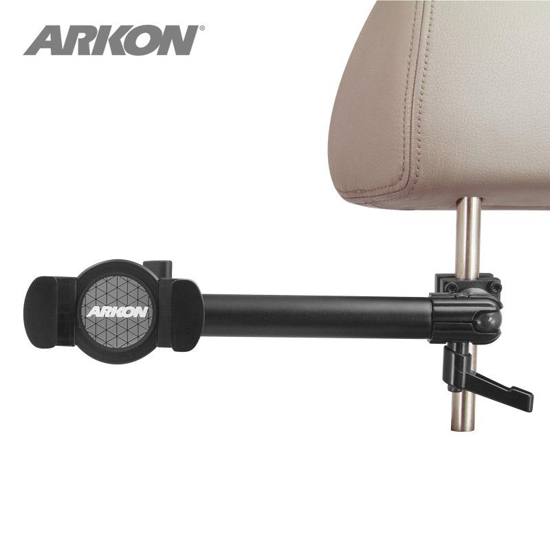 A black RoadVise® Phone Holder with Car Headrest Mount attaches to a tan seat headrest post using adjustable clamps and an extending arm, ideal for backseat entertainment. The Arkon logo is visible on the holder.