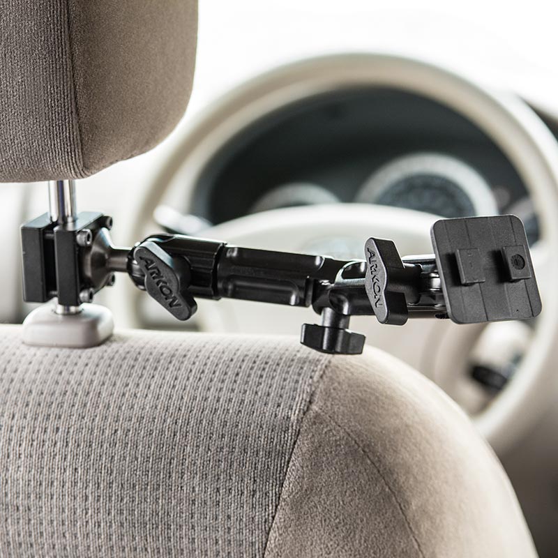 The Heavy-Duty Headrest Mounting Pedestal with Multi-Angle 8 Arm securely holds your tablet to a car’s headrest, extending forward with the dashboard and steering wheel visible in the background.