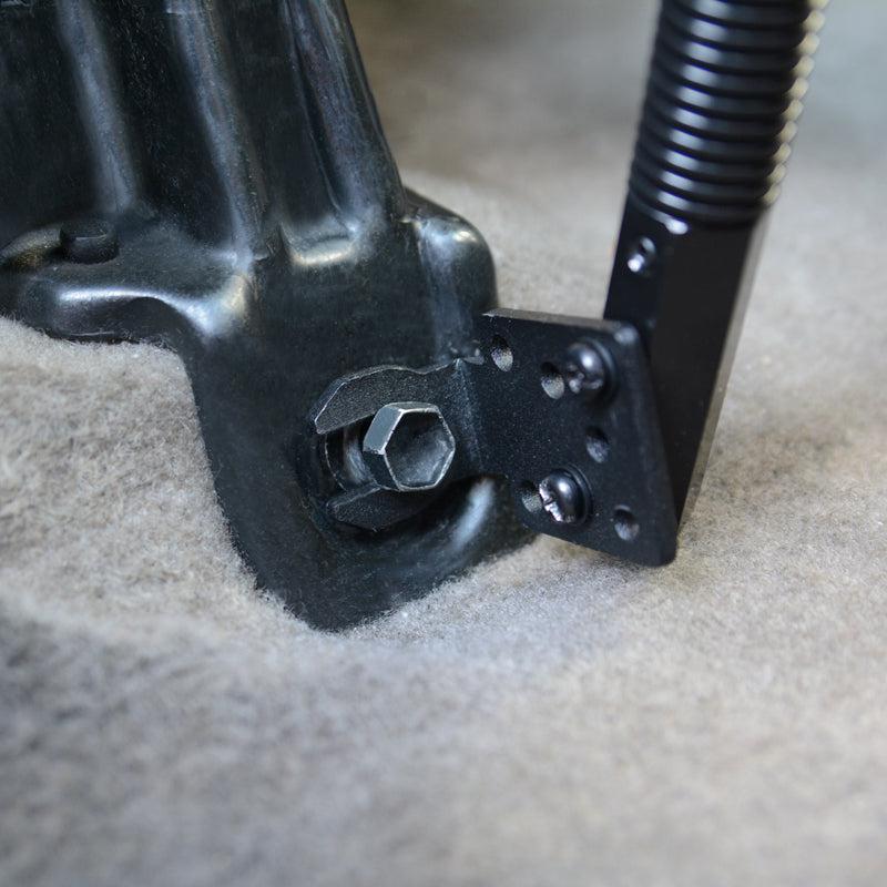 Close-up of the Heavy-Duty Truck Seat Rail Floor Mount Pedestal - Dual-T Compatible, featuring a metal bracket bolted to carpet and a black spring-loaded lever attached to the bracket with screws.