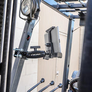 The LockVise™ Locking Forklift Front Guard Tablet Mount with 5 Robust™ Shaft is installed on a forklift’s metal frame, with nearby levers and a work light clearly visible.
