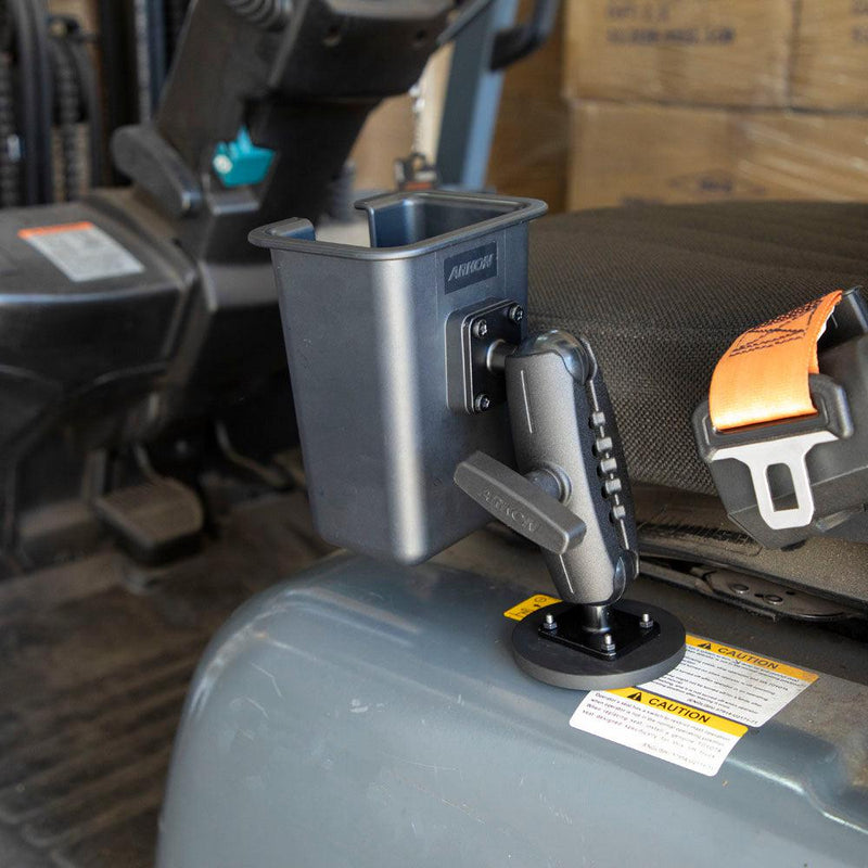 A Magnetic Mount with Barcode Scanner Holster Holder is attached beside the operators seat, near an orange safety seatbelt. Cardboard boxes are stacked in the background.