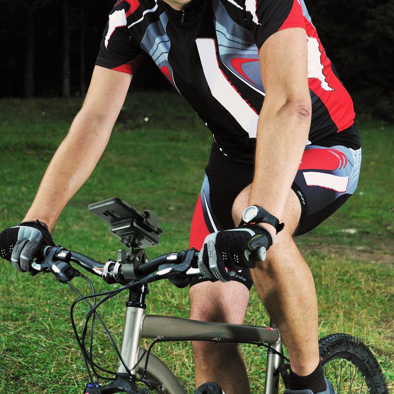 A cyclist in red, black, and white rides on grass, gripping the handlebars and wearing gloves. A Mega Grip™ Phone Holder with Clamp Mount is attached to the bike, securing a device. The upper part of the rider’s head is not visible.