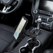 A Mega Grip™ Universal Car Cup Holder Phone Mount holds a smartphone securely in the center console, displaying a map for hands-free navigation with the steering wheel and gear shift visible.