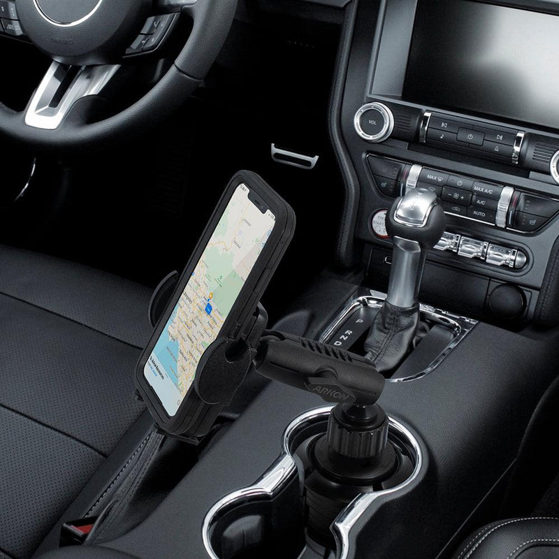 A Mega Grip™ Universal Car Cup Holder Phone Mount holds a smartphone securely in the center console, displaying a map for hands-free navigation with the steering wheel and gear shift visible.