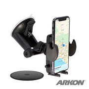 A black Mega Grip™ Windshield Phone Mount securely holds a smartphone with a map. Featuring an adjustable grip and suction cup base, this car mount keeps your device steady. The Arkon logo is visible in the lower right corner.