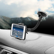 An iPhone is mounted on the Mobile Grip 2 Windshield Suction Car Mount with an 8.5 arm, showing a navigation map. The universal mount attaches to the dashboard, and snowy mountains are visible through the windshield.