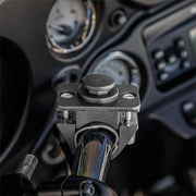 Close-up of the OCTO™ Series Motorcycle or Bicycle Handlebar Mount attached to a chrome handlebar, showing its locking mechanism. The blurred dashboard with gauges is visible in the background. Octagon design allows versatile mounting options.