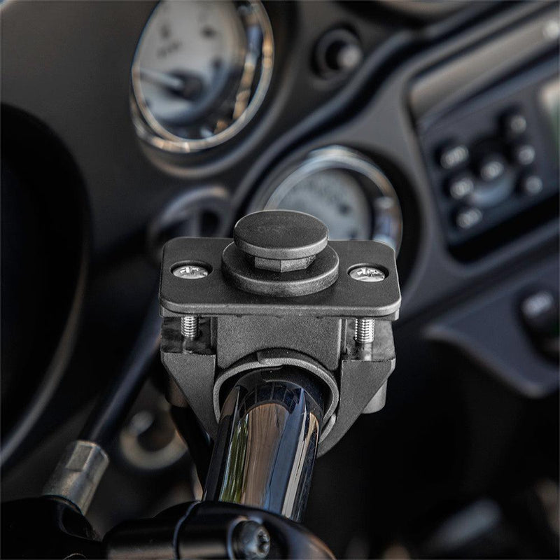Close-up of the OCTO™ Series Motorcycle or Bicycle Handlebar Mount attached to a chrome handlebar, showing its locking mechanism. The blurred dashboard with gauges is visible in the background. Octagon design allows versatile mounting options.
