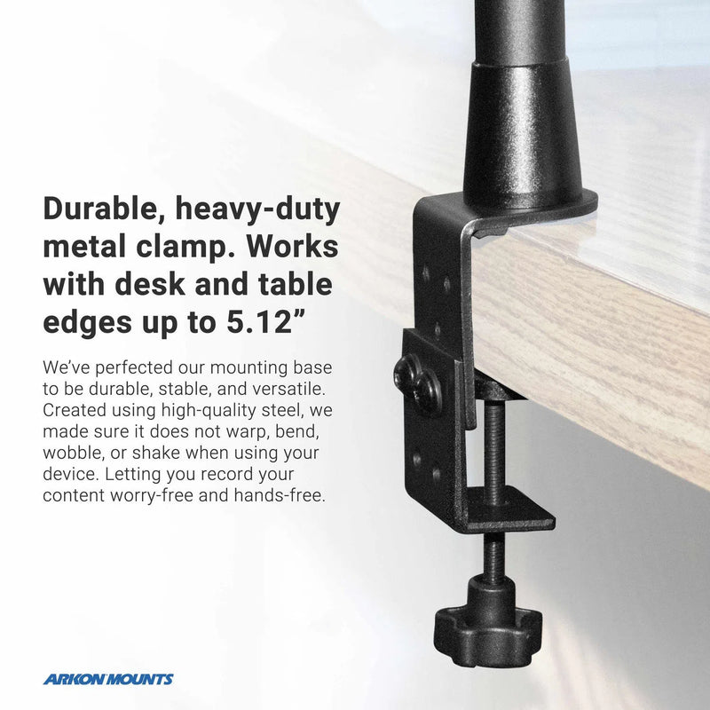 A black metal clamp attaches the Remarkable Creator™ Studio Mount – Overhead Camera Mount to a wooden desk edge (up to 5.12”). Text highlights stability and durability. The Arkon Mounts logo appears in the bottom left corner. Includes camera, tablet, and phone holder.