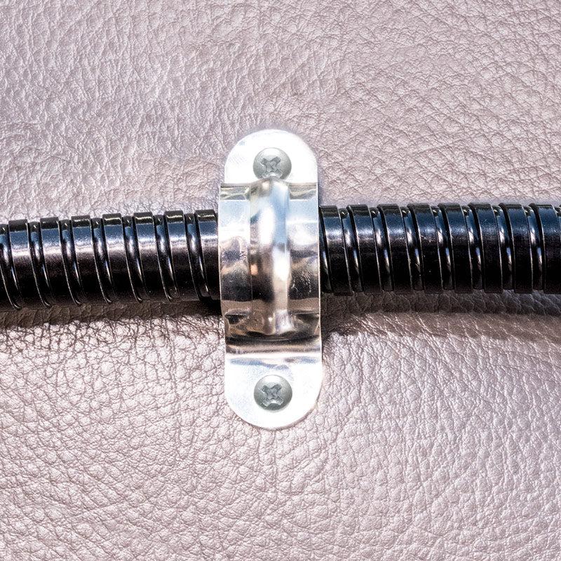 The Replacement Metal Conduit for Seat Rail Mounts is secured to a textured brown surface with a metal clamp and two screws, providing vibration prevention similar to a floor mount gooseneck.