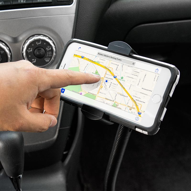 A hand touches a smartphone, mounted above the car’s gear shift and climate controls in a RoadVise® XL Car Seat Rail or Floor Mount, with a navigation map on the screen.