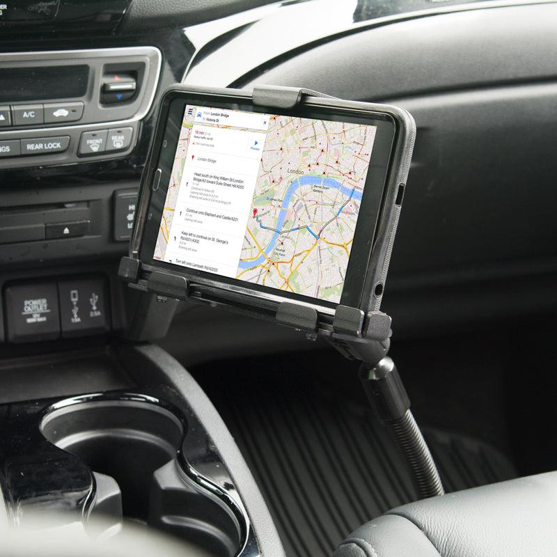A smartphone in a LockVise™ Metal Locking Seat Rail Tablet Mount with 18 Aluminum Gooseneck and 3.75 shaft shows a navigation map. The heavy-duty mount is attached near the center console beside cup holders, with dashboard controls visible.