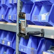 A smartphone is secured on a shelf with the LockVise™ Locking Magnetic Tablet Mount for inventory tasks, surrounded by blue plastic bins filled with small parts.