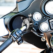 Close-up of a motorcycle handlebar featuring mounted controls and a black phone/GPS holder attached with the Robust™ Mount Clamp Post with 25mm (1) Ball, positioned in front of the bike’s gauges and dashboard.