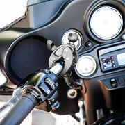 Close-up of a motorcycle handlebar with the Robust™ Mount Clamp Post featuring a 25mm (1) ball, shown mounted near the speedometer, tachometer, and dashboard control buttons.