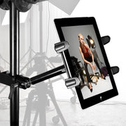 The Slim-Grip® Tablet Holder with Clamp Base and Extension Arm displays a fashion photo of a woman in a red top and black pants, posing in a professional photo studio with lights and equipment visible in the background.