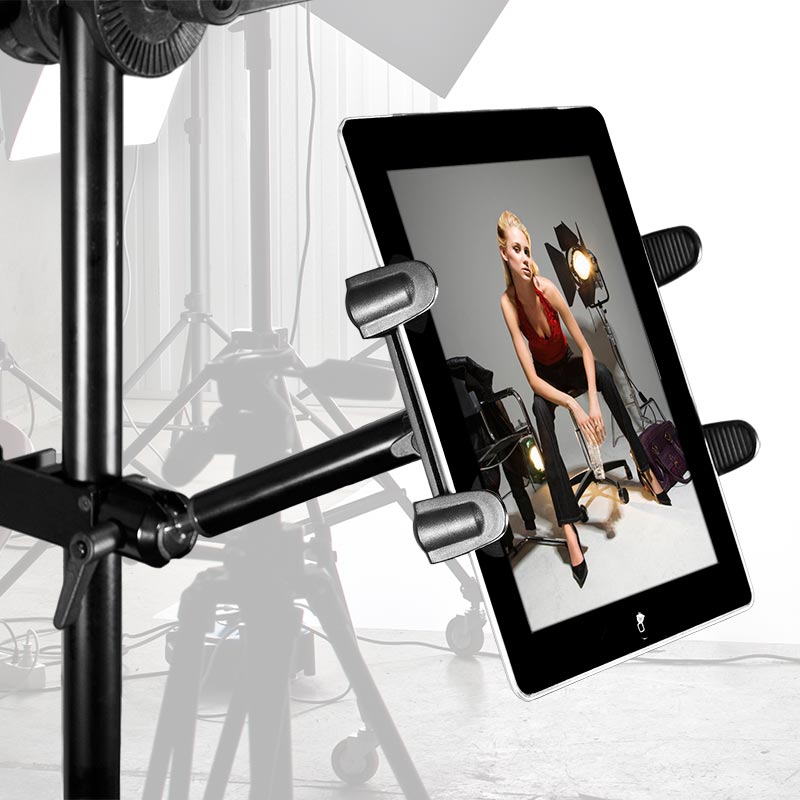 The Slim-Grip® Tablet Holder with Clamp Base and Extension Arm displays a fashion photo of a woman in a red top and black pants, posing in a professional photo studio with lights and equipment visible in the background.