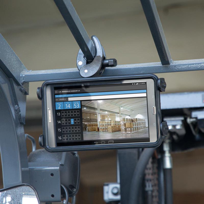 The Slim-Grip® Tablet Holder with Clamp Mount and Security Knob Shaft secures a tablet to industrial equipment, displaying warehouse management software with a calendar and a warehouse image filled with pallets.