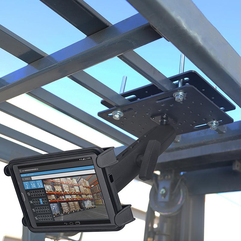 A Slim-Grip® Tablet Holder with Forklift Overhead Guard Mount and 8.5 Metal Shaft secures a rugged tablet to the overhead metal framework of a forklift, displaying warehouse inventory on its screen against a blue sky backdrop.