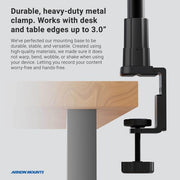 The Slim-Grip® Tablet Holder with Heavy-Duty Clamp Mount is securely attached to a wooden desk, showcasing its strong black metal build and ability to fit desk or table edges up to 3.0 inches thick for reliable device mounting.