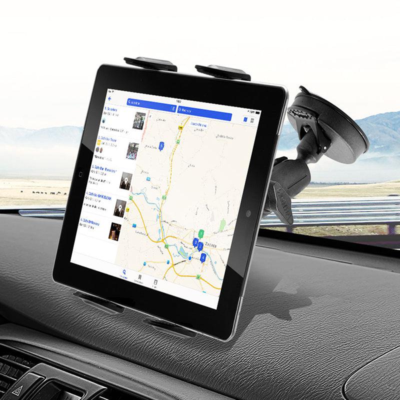A Slim-Grip® Tablet Holder with Suction Cup Windshield Mount keeps a tablet upright on the car dashboard, displaying a map with driving directions while the road and landscape are visible outside.