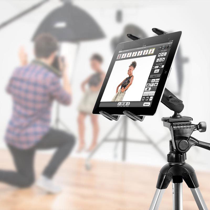 A photographer kneels to capture a woman posing in a studio, with a Slim-Grip® Tripod Tablet Mount with 3.75 Shaft holding a tablet that displays her image and photo editing tools.