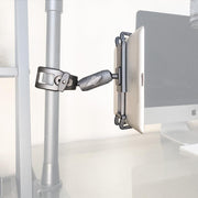 A Slim-Grip® Ultra Phone or Midsize Tablet Clamp Mount with Security Knob holds a tablet on a vertical metal pole beside a desk with a computer monitor in the background.