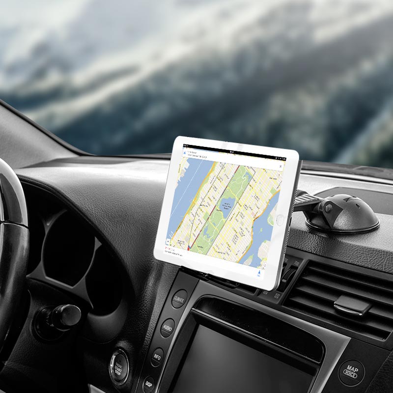 A Slim-Grip® Ultra Sticky Suction Windshield or Dash Phone Car Mount securely holds a tablet displaying a map on a car dashboard, with the steering wheel, controls, and a blurred outdoor scene visible through the windshield.
