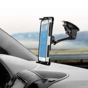 An iPhone secured to the dashboard with the Slim-Grip® Ultra Sticky Suction Windshield or Dash Phone Car Mount displays a weather app, while the blurred road and landscape are visible through the windshield in the background.