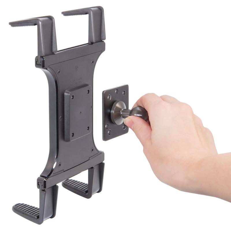 A hand is attaching the Slim-Grip® Universal Tablet Holder - AMPS Pattern Compatible to a wall mount using a round metal knob and the 4-Hole AMPS Mount pattern for secure installation.